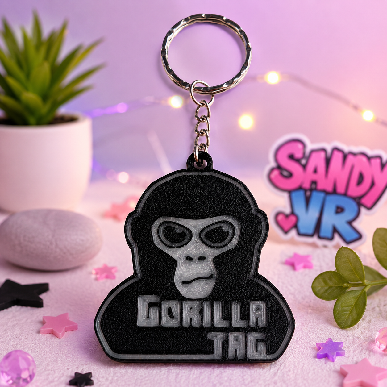 Close-up of a Gorilla Tag 3D printed keychain displayed in a colorful SandyVR-themed setup with decorative stars, lights, and gaming-inspired elements.