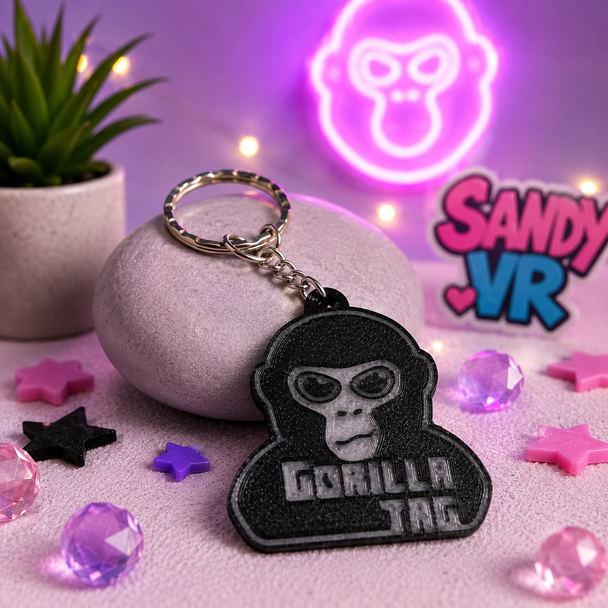 Gorilla Tag 3D printed keychain displayed on a decorative pink background with crystals, stars, and SandyVR branding.